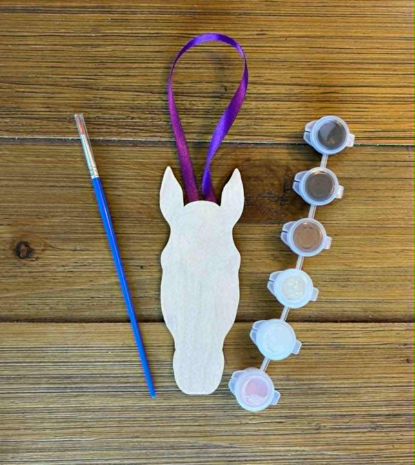 Wooden horsehead paint project with paintbrush, paint set, and a ribbon hanger